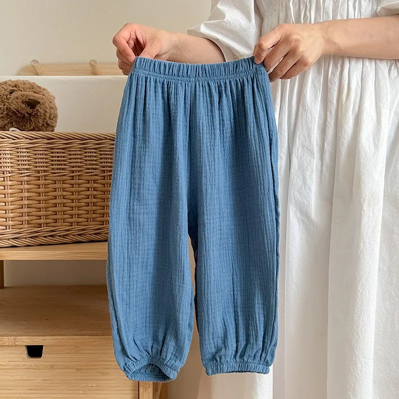 Blue baby pants being held up in front of a neutral background