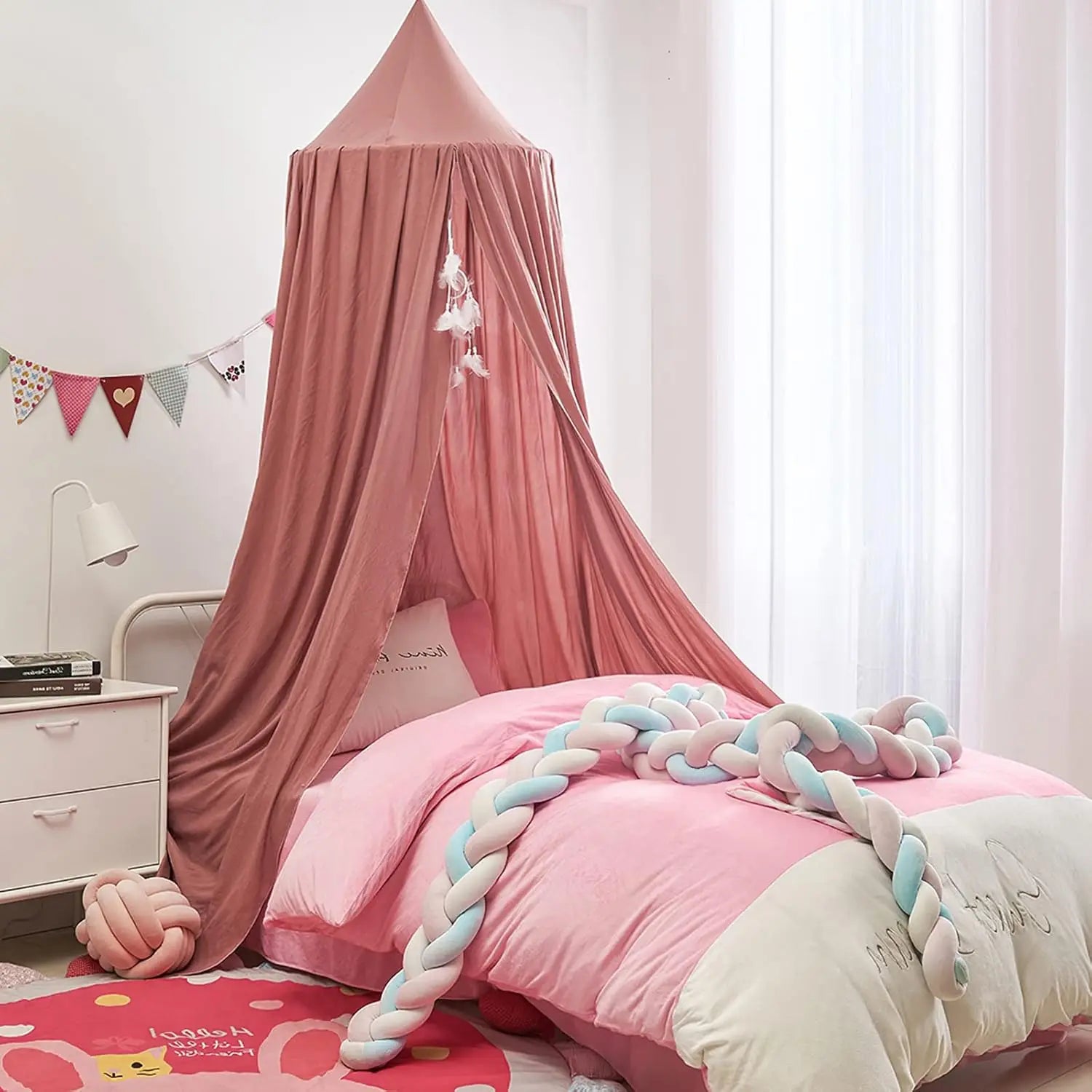 Children's bedroom with pink canopy over a bed, colorful decorations, and a nightstand.